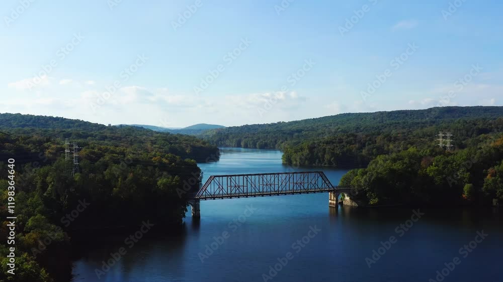 Drone fly-out capturing a peaceful walking bridge spanning the New Croton Reservoir, surrounded by vibrant autumn forests in Westchester County, New York. Drone fly-out capturing a peaceful walking bridge spanning the New Croton Reservoir, surrounded by vibrant autumn forests in Westchester County, New York.