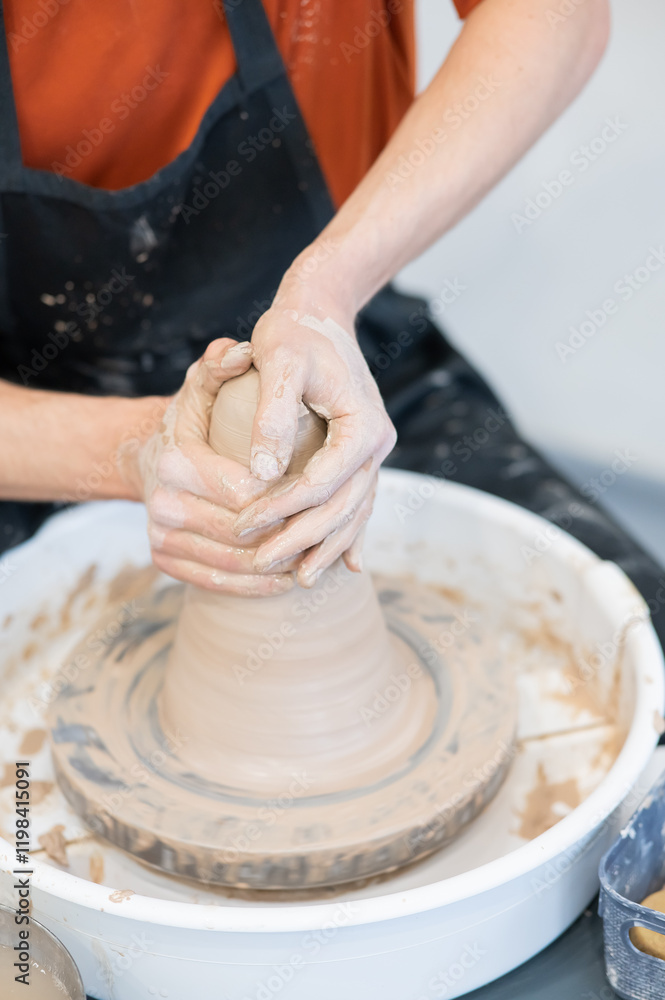 Close-up of a potter's hands working on a pottery wheel. Vertical photo. Close-up of a potter's hands working on a pottery wheel. Vertical photo.