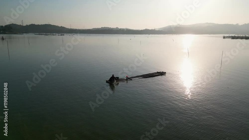 A fisherman casts his net into the calm waters of Rawa Jombor in the early morning, as soft sunlight illuminates the serene lake and surrounding natural beauty. photo