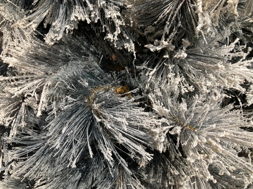 The branches and leaves of the fake pine tree are covered in fake snow, giving it a grayish white color, and the golden ornaments on the tree are shining
