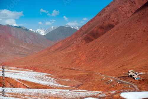 A mountain range with a road leading to a small house photo