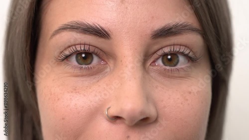 A beautiful young girl opens her eyes after eyelash lamination. Close-up, slow motion