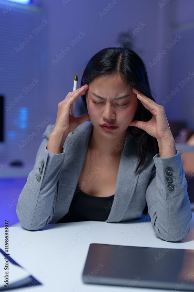 Young asian manager suffering from headache working with laptop late at night in office, massaging temples, tired and exhausted, suffering from migraine, having painful feelings Young asian manager suffering from headache working with laptop late at night in office, massaging temples, tired and exhausted, suffering from migraine, having painful feelings