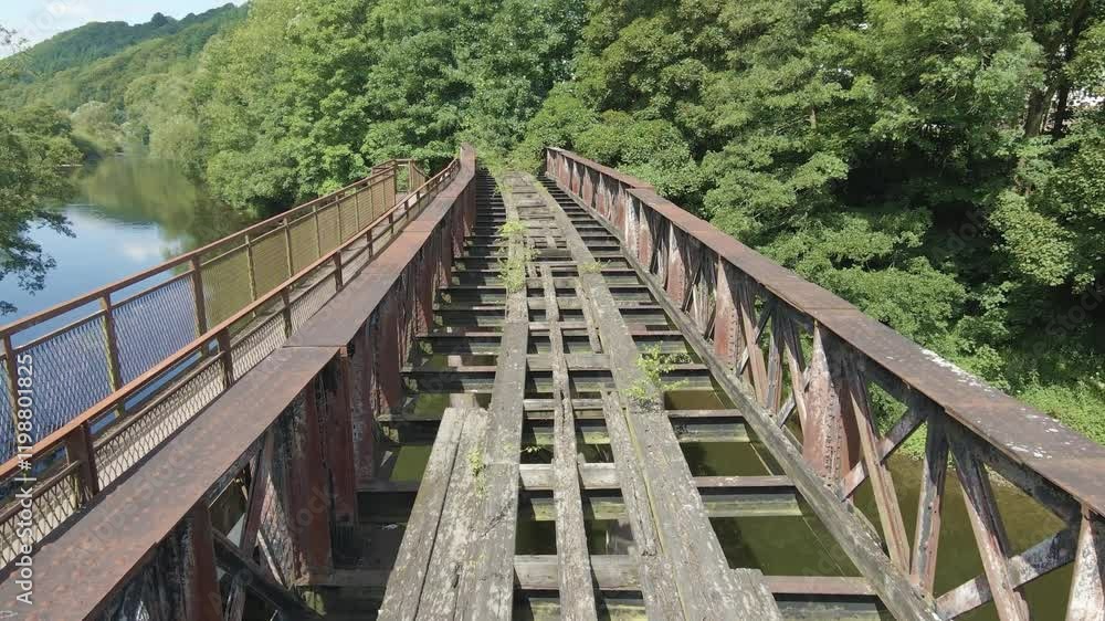 Old steel bridge over the River Wye, Wales, United Kingdom. Low drone shot slowly moving forwards above historic bridge. Surrounded by forested riverbanks. 3 of 4 Old steel bridge over the River Wye, Wales, United Kingdom. Low drone shot slowly moving forwards above historic bridge. Surrounded by forested riverbanks. 3 of 4