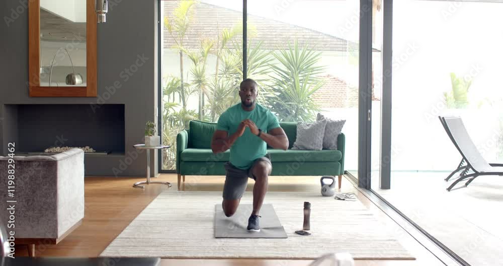 Strong and fit man doing lunges on yoga mat in modern living room Strong and fit man doing lunges on yoga mat in modern living room