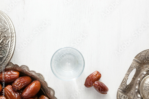 Obraz na płótnie Top view on silver plate with date fruits and glass of water on a white wooden background. Ramadan background. w salonie