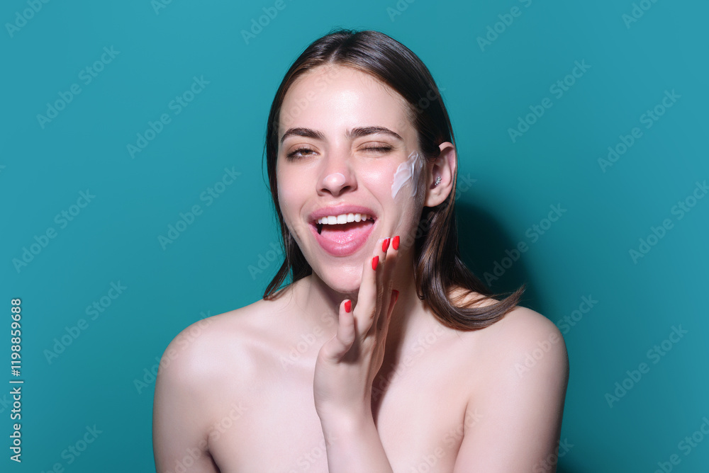 Obraz premium Skin care. Woman applying face cream, studio portrait. Beautiful model with moisturizing cream anti age cream on perfect soft skin. Beauty cosmetic product industry.