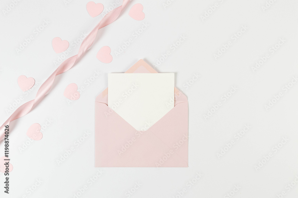 Top view of pink envelope, white card and pink ribbon on white background. Valentine's day, pink hearts, love. Shiny rolled fabric, silk and satin material. Copy space, flat lay, post. Top view of pink envelope, white card and pink ribbon on white background. Valentine's day, pink hearts, love. Shiny rolled fabric, silk and satin material. Copy space, flat lay, post.