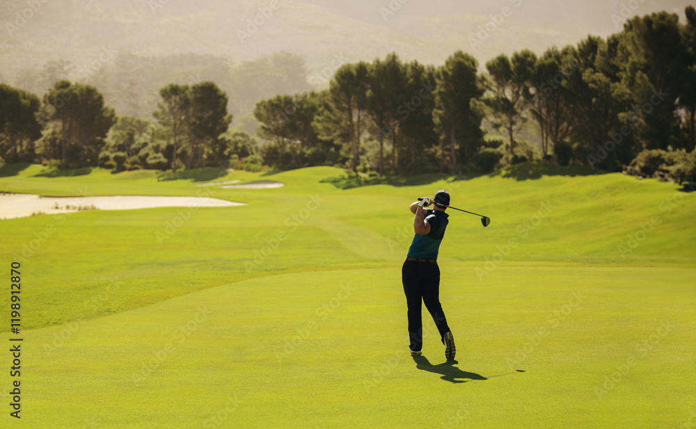 Golfer swinging with precision and follow through on a vibrant golf course fairway shot during a sunny day Golfer swinging with precision and follow through on a vibrant golf course fairway shot during a sunny day
