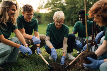Happy volunteers planting a tree in the park