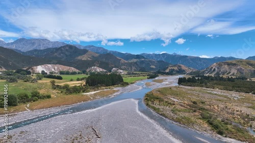 Aerial flies across the broad braided Buller River as it forks into two channels amongst wide valley and vast mountain backdrops, West Coast, Westport, Buller Gorge Aotearoa New Zealand photo