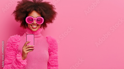 Smiling woman in a bright pink sweater and oversized sunglasses holding a pink smartphone. Monochromatic pink background enhances the bold and fun modern aesthetic