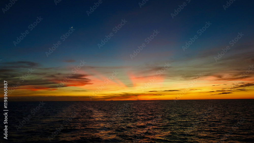 Fototapeta premium Sunset over the sea. View of the rays of the setting sun over the surface of the ocean. Sunset sea.