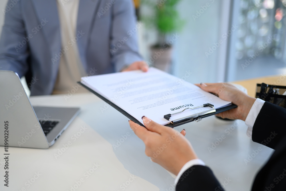 Close up of a candidate handing over resume to the interviewer during formal job interview Close up of a candidate handing over resume to the interviewer during formal job interview