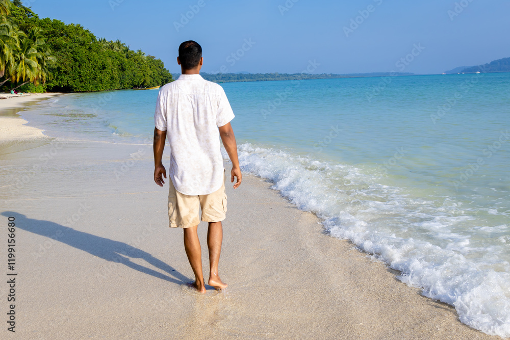 isolated man walking at pristine white sand beach with rolling sea waves at morning from flat angle isolated man walking at pristine white sand beach with rolling sea waves at morning from flat angle