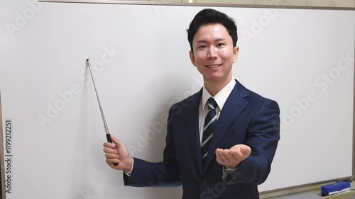 ホワイトボードでプレゼンするスーツ姿の男性講師
