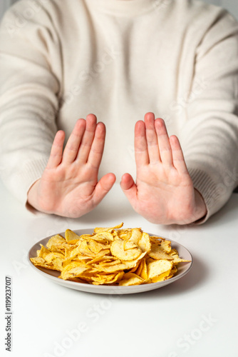 Woman pushing away plate with fried chips. No to fast food. Healthy eating concept. Rejecting junk food for vegetables and healthy eating.