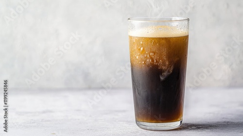 Dark beverage with bubbles served in clear glass, capturing refr photo