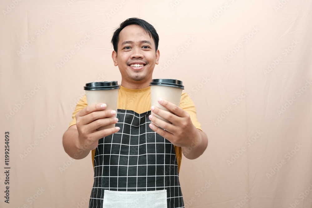 A smiling Asian man barista in a checkered apron holding two takeaway coffee cups, presenting them forward. A smiling Asian man barista in a checkered apron holding two takeaway coffee cups, presenting them forward.