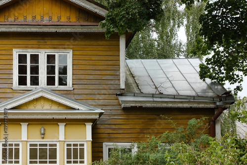 It is an old wooden European residential building up close with details of white wooden windows and exterior. Summer time.