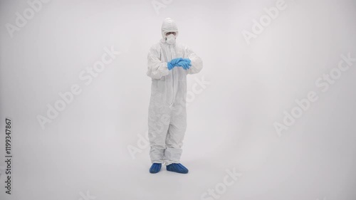 A scientist in PPE cleaning hands and coming closer on a white background