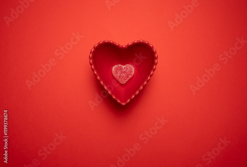 Heart-shaped gummy candies in a heart-shaped bowl on a vibrant red background, symbolizing love and romance. Ideal for Valentine's Day, weddings, anniversaries, and romantic celebrations.