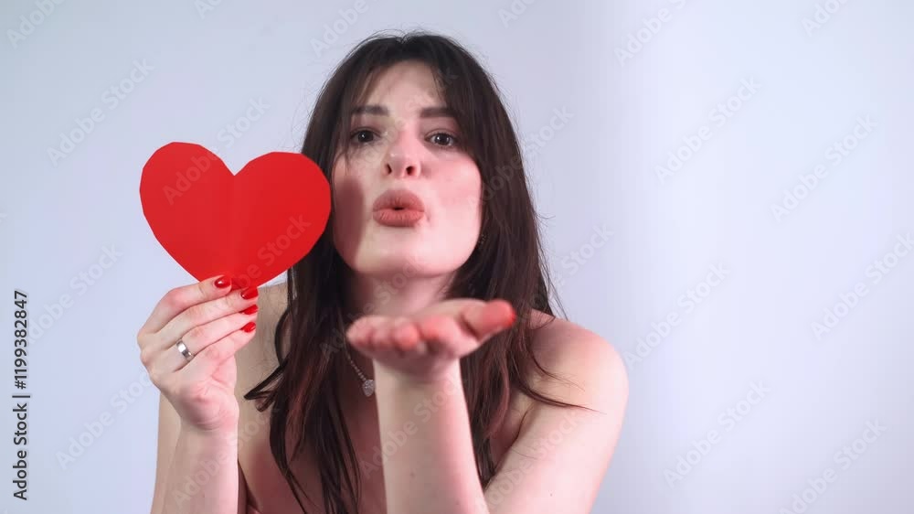 Woman in pink outfit sending a kiss, holding a Valentine card, symbol of Valentine's Day celebration. Woman in pink outfit sending a kiss, holding a Valentine card, symbol of Valentine's Day celebration.