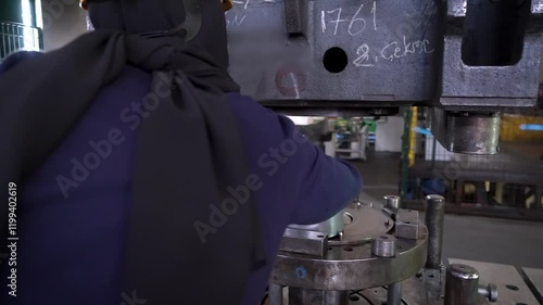 Close up view of an employee working on the hydraulic press process in a heavy industry factory.