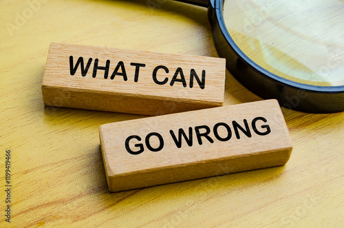 Photos Top view of What Can Go Wrong text on wooden blocks with magnifying glass