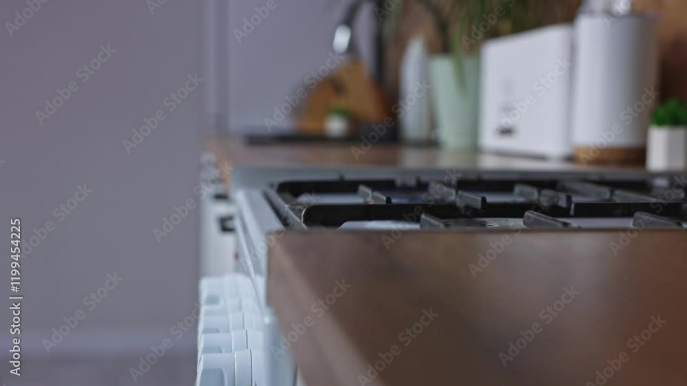 Hand holding dark frying pan and shaking and tossing the contents of the pan stirring it, then turns off the stove and the gas fire under the pan goes out, side view against the background of a white Hand holding dark frying pan and shaking and tossing the contents of the pan stirring it, then turns off the stove and the gas fire under the pan goes out, side view against the background of a white