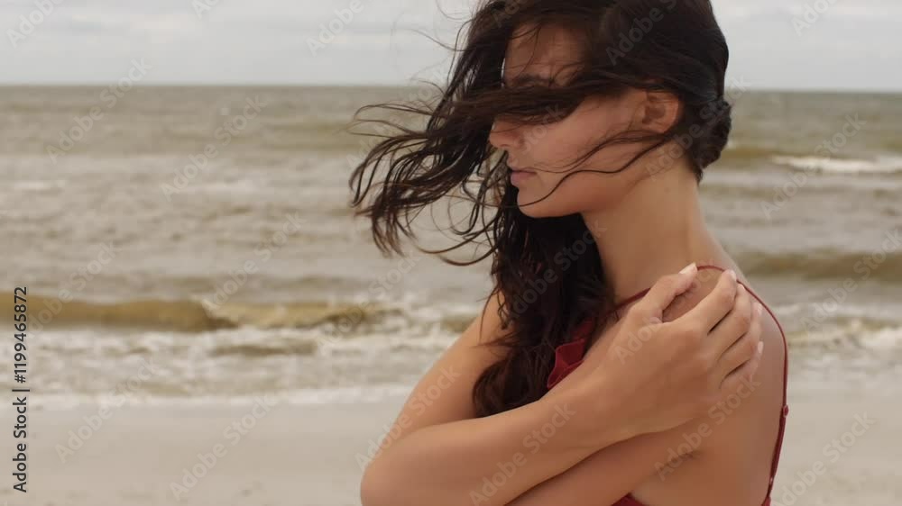 A thoughtful woman in a red dress embraces herself on a windy shore, reflecting on her thoughts. Ideal for promoting themes of introspection, solitude, and beauty in travel, fashion, and lifestyle A thoughtful woman in a red dress embraces herself on a windy shore, reflecting on her thoughts. Ideal for promoting themes of introspection, solitude, and beauty in travel, fashion, and lifestyle
