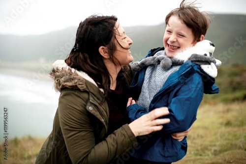 Happy Caucasian mother and son enjoying outdoors nature. Mother and son having fun at coast. Son and mother hugging at the coast. Family trip. Family vacation. Mother and son outdoor activity photo