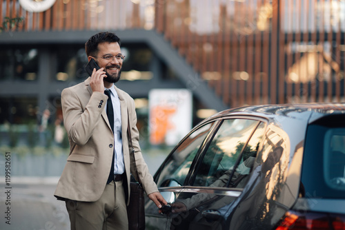 Businessman talking on phone opening car door in city