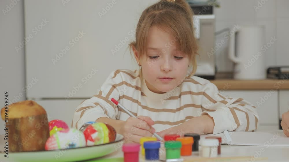 Adorable daughter in striped sweater draws pictures with colored pencils. Close-up. Mother and daughter have a great time together. Adorable daughter in striped sweater draws pictures with colored pencils. Close-up. Mother and daughter have a great time together.