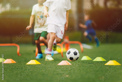 Фотография Young Boy Running With Soccer Ball Through Training Obstacle Course