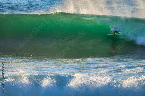 Surfer ridding a wave in Coxos in Ericeira, Portugal. A surfer riding a powerful wave with the spray and ocean in the background. photo