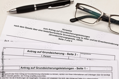 Antragsformulare zur Grundsicherung mit Kugelschreiber und Lesebrille