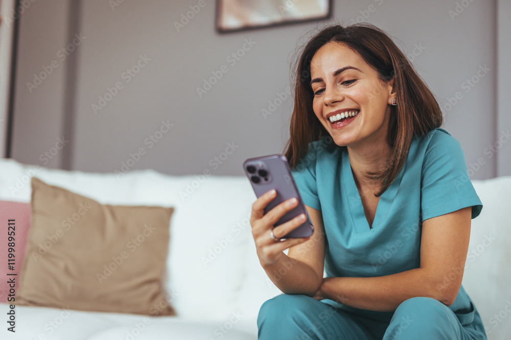 Happy Woman in Scrubs Using Smartphone on Comfortable Sofa Happy Woman in Scrubs Using Smartphone on Comfortable Sofa