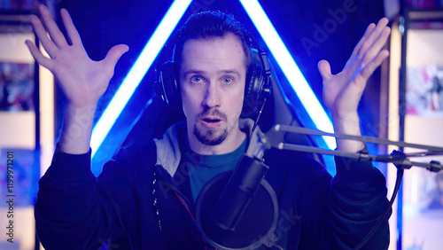 Male gaming streamer mind blowing with hands surrounded with neon lights room photo