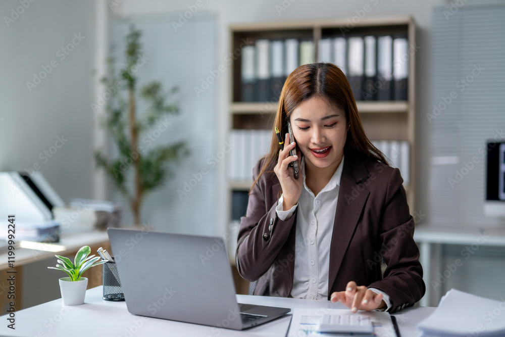 A woman is talking on her cell phone while sitting at a desk A woman is talking on her cell phone while sitting at a desk