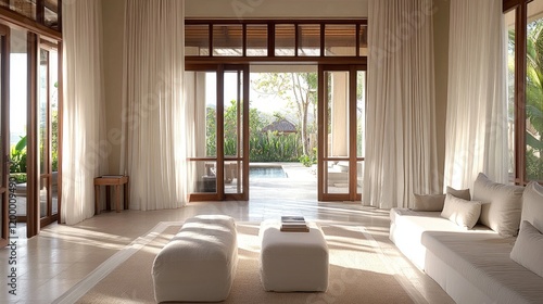 A serene hall with light-toned furniture  soft curtains  and a large glass door leading to a terrace.