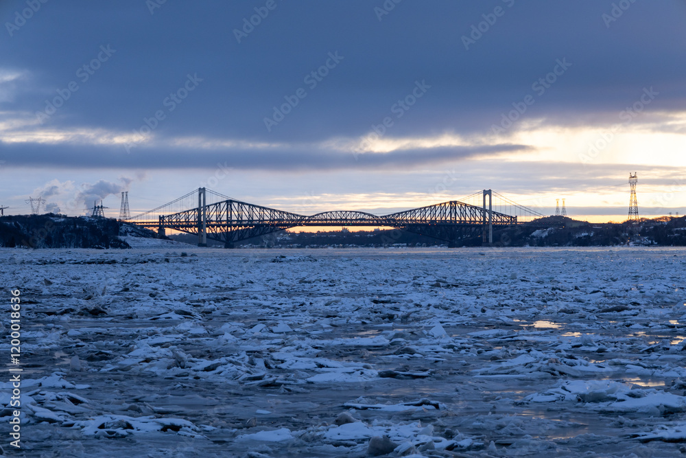 Fototapeta premium The 1970 suspension Pierre-Laporte Bridge and 1919 steel truss Quebec Bridge in silhouette during a blue hour winter sunrise on the St. Lawrence River, Cap-Rouge area, Quebec City, Quebec, Canada