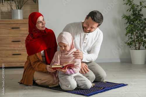 Muslim family with Quran praying on mat at home photo