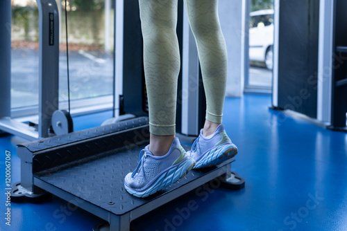 Fototapeta Muscular female athlete performing calf raises on exercise machine, strengthenin