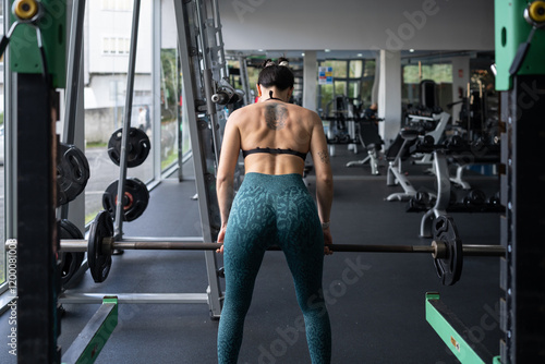 Muscular female weightlifter executing heavy barbell deadlift, demonstrating intense physical strength within modern fitness training environment