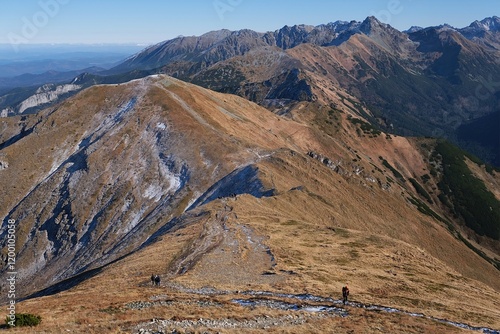 Panorama of Czerwone Wierchy range from around Kasprowy Wierch Peak, Tatras Mountains, Poland. During trekking red trail on sunny autumn day. Little silhouettes of people on trail.