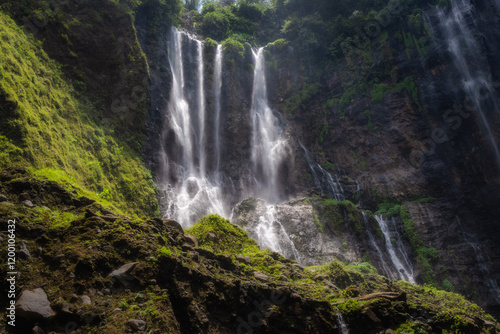 This truly majestic Tumpak Sewu Waterfall is beautifully framed by vibrant, colorful foliage, showcasing the incredible beauty of nature in a tranquil, idyllic landscape setting, East Java, Indonesia