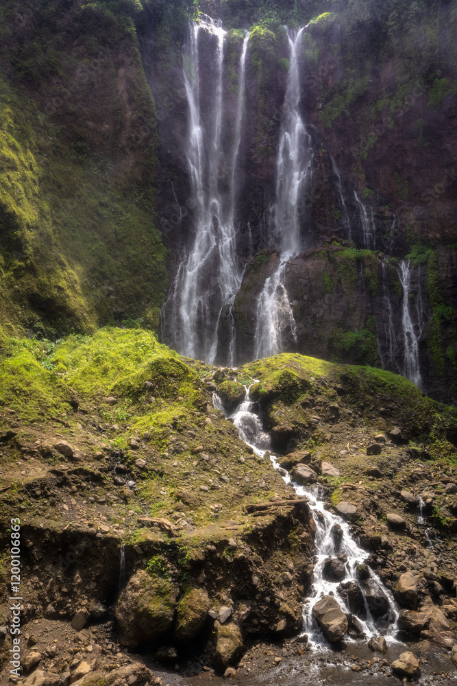 Obraz premium A stunning and majestic Tumpak Sewu Waterfall cascades gracefully down rugged rocky cliffs, enveloped by lush, vibrant greenery, showcasing the breathtaking beauty of nature, East Java, Indonesia