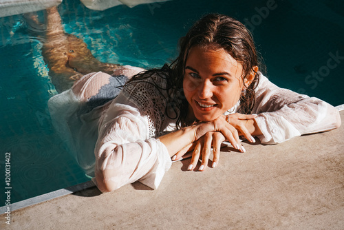 A close-up image of a fashionable woman in a swimming pool with wet hair and an elegant white blouse shows her beauty and sexuality. photo