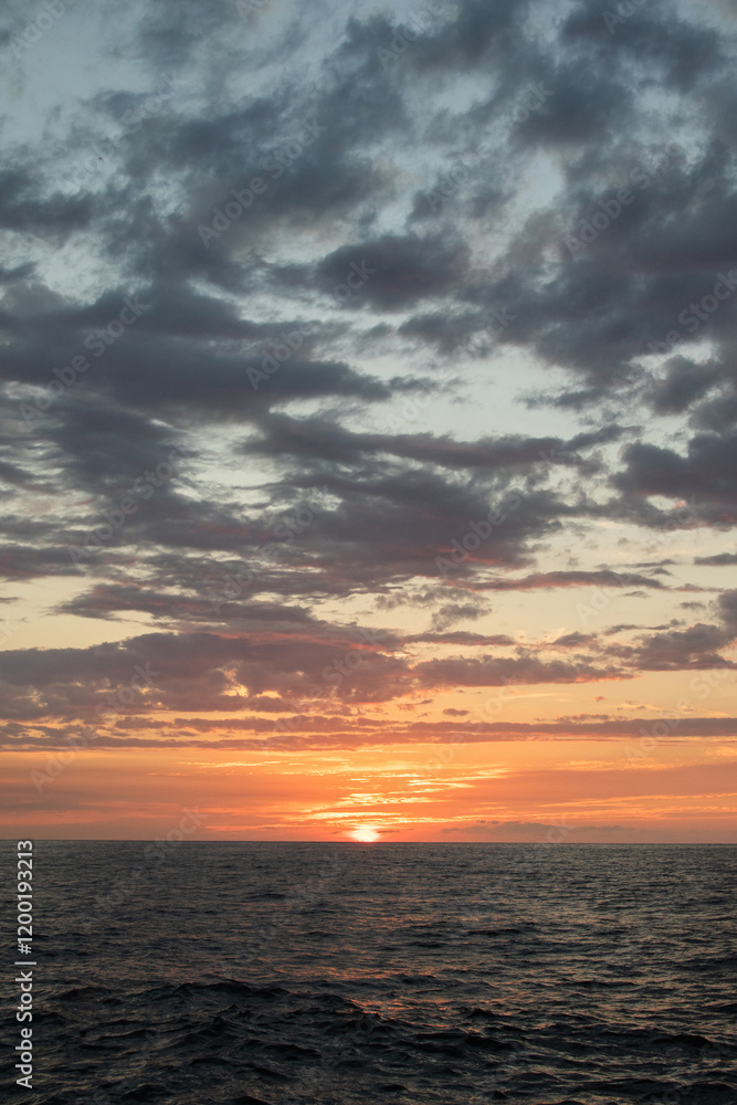 Naklejka premium Ocean Sunset with Vibrant Sky and Clouds